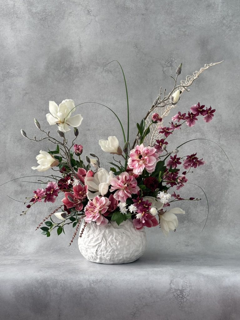 ピンクと白の花をあしらった、白い花器のフラワーアレンジメント